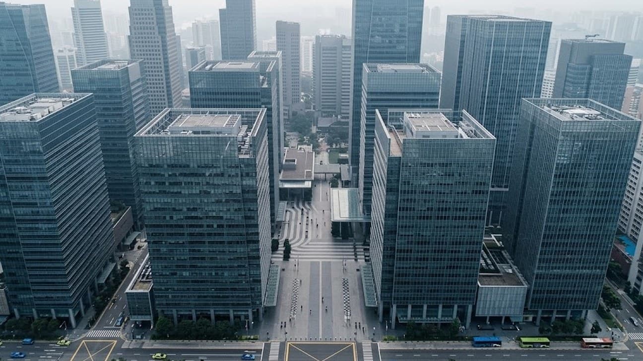 Photorealistic aerial photograph shot directly overhead of Singapore's central business district, showing a grid of glass office towers and a wide pedestrian plaza under soft overcast midday light, with small distant pedestrians crossing below.