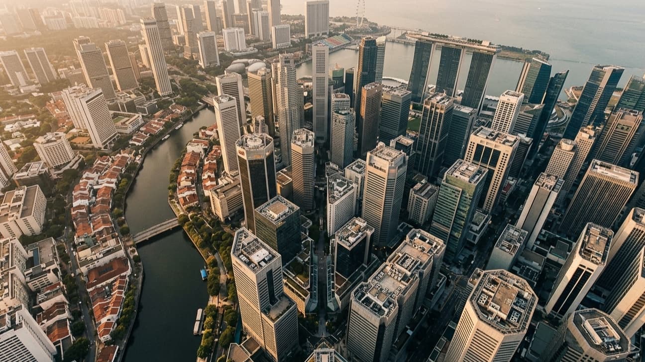 Aerial view of Singapore's financial district at golden hour, with the Singapore River winding through dense towers of Raffles Place and Marina Bay